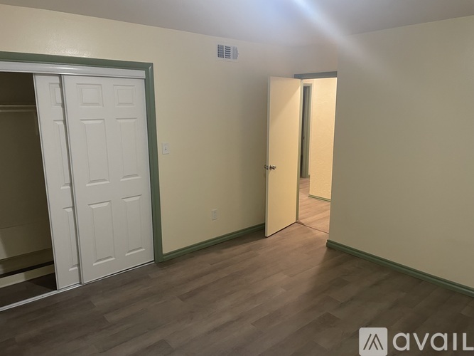 A room with a white door and a wooden floor.