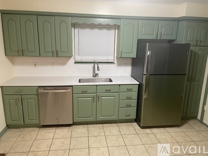 A kitchen with green cabinets and a black refrigerator.