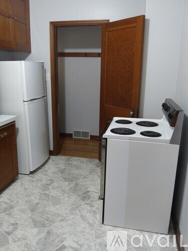 A kitchen with a white fridge, a white stove and a wooden door.