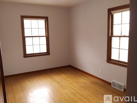 A room with wooden floors and two windows.