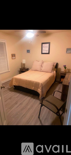 A bedroom with a bed, chair, and a framed picture on the wall.