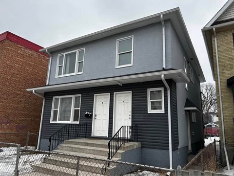 A grey house with a white door and windows.