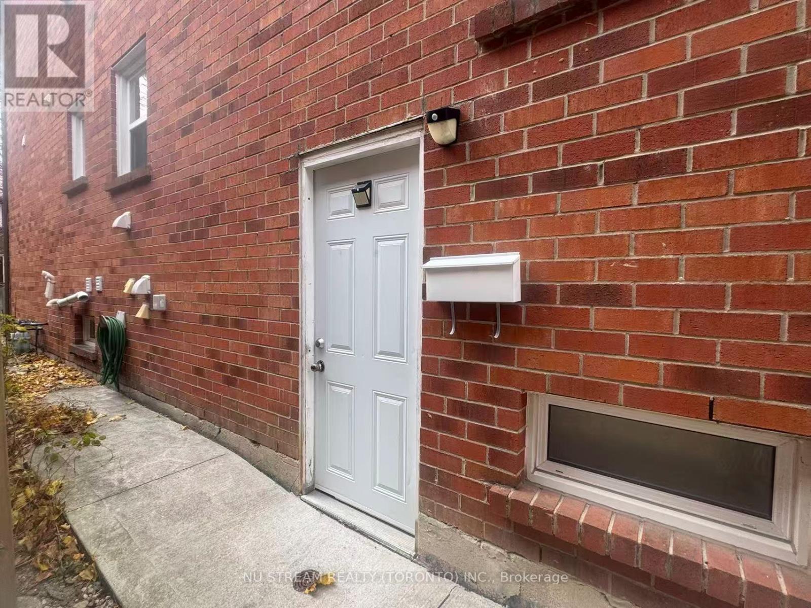 A red brick house with a white door and a small window on the side.