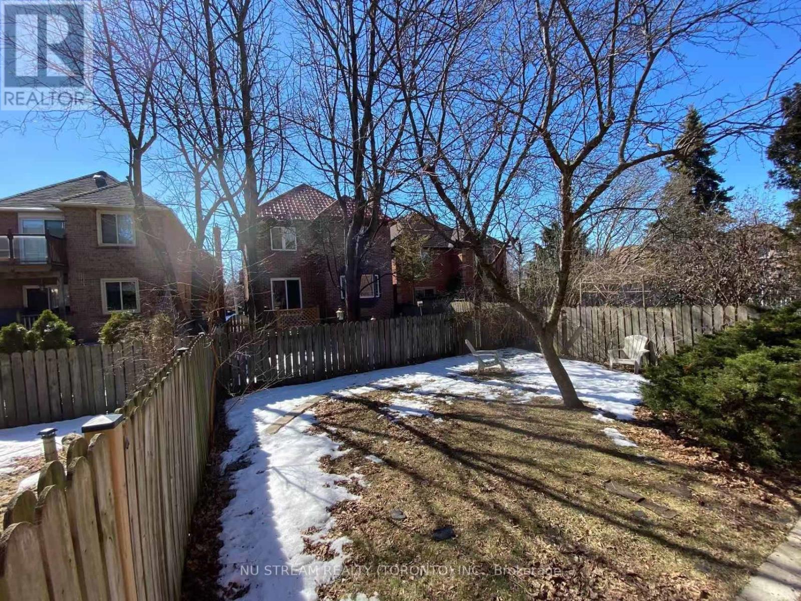 A backyard with a wooden fence and a tree with no leaves.