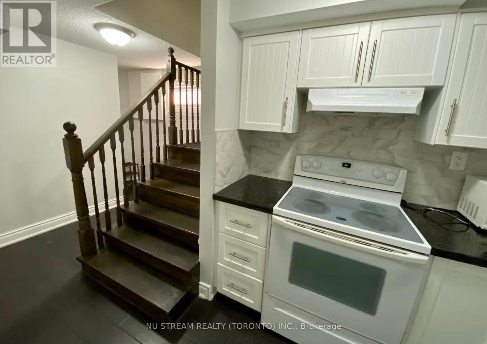 A kitchen with a stove and a staircase.