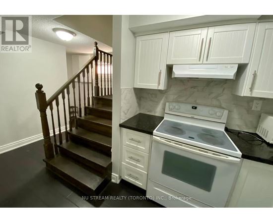 A kitchen with a stove and a staircase.