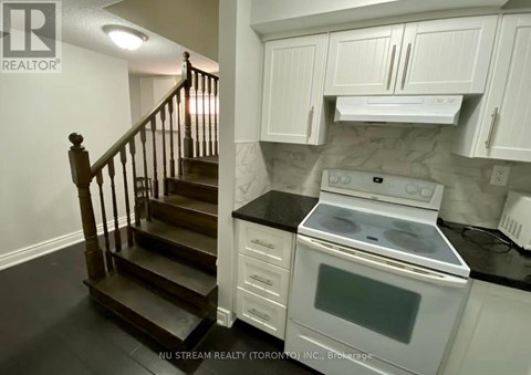 A kitchen with a stove and a staircase.