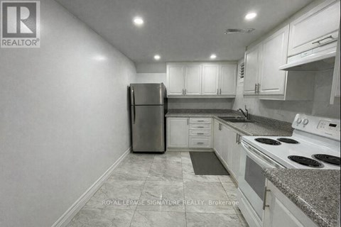 A kitchen with white cabinets and a black refrigerator.