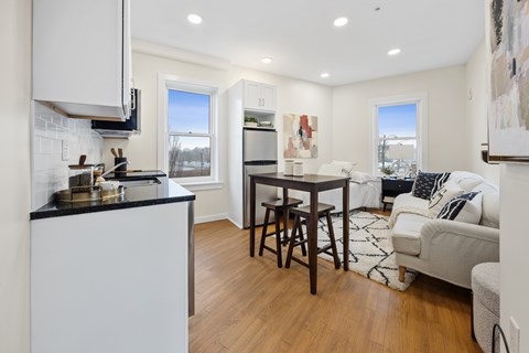 A kitchen with white cabinets and a black countertop.
