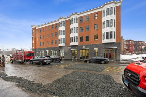 A red truck is parked in front of a multi-story building.