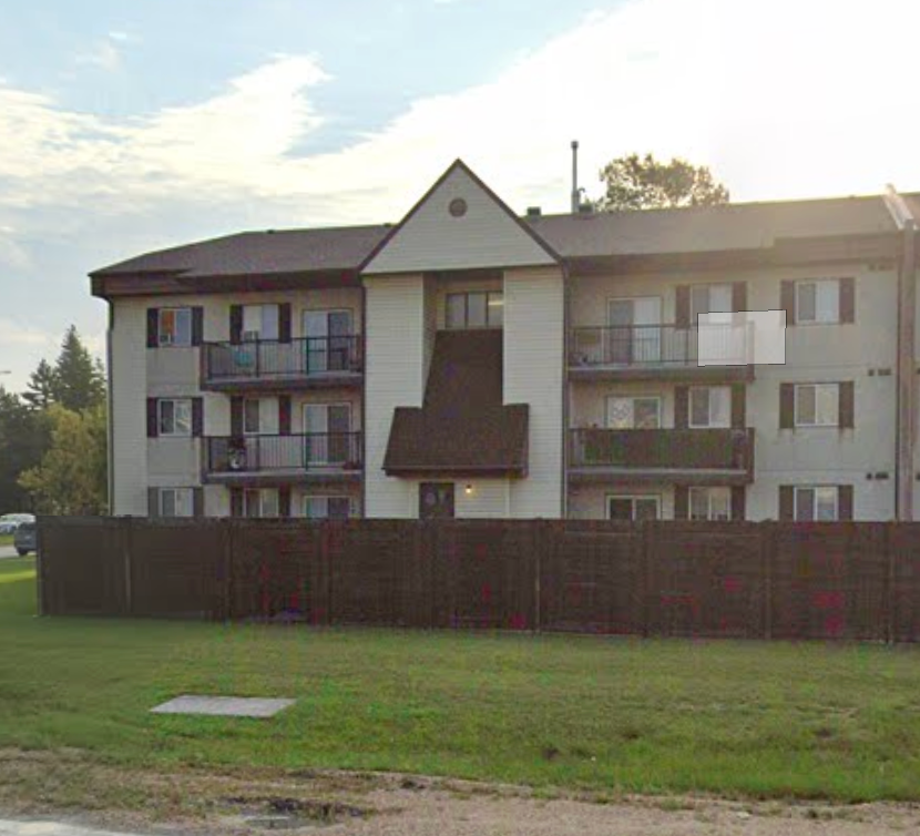 Apartment building with a brown fence in front.
