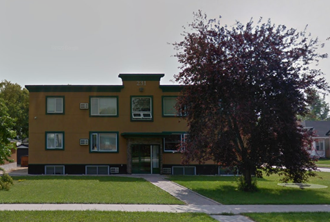 A brown building with a tree in front of it.