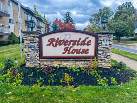 A sign for Riverside House is in front of a building.