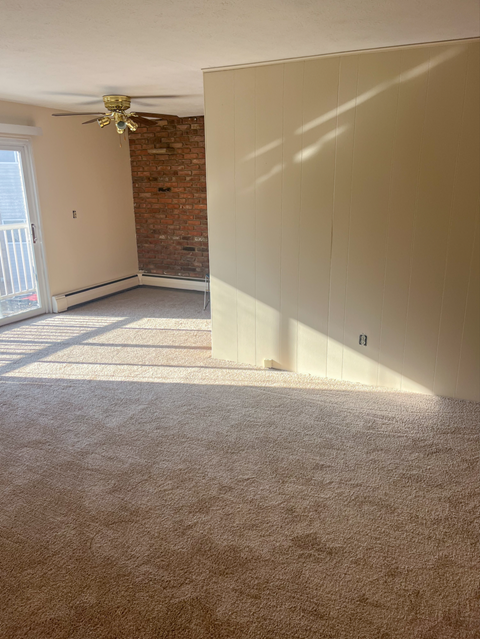 A room with a carpeted floor and a ceiling fan.
