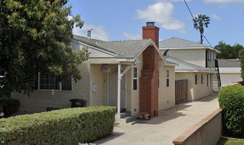 A house with a brick chimney and a grey roof.