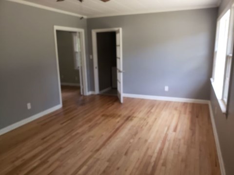 A room with wooden floors and two open doors.