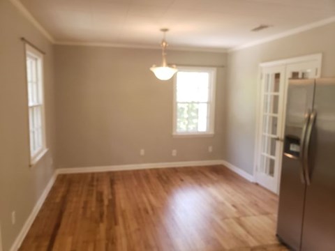 A kitchen with a wooden floor and a refrigerator.