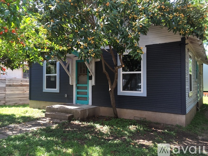 A small house with a blue door and a tree in front.