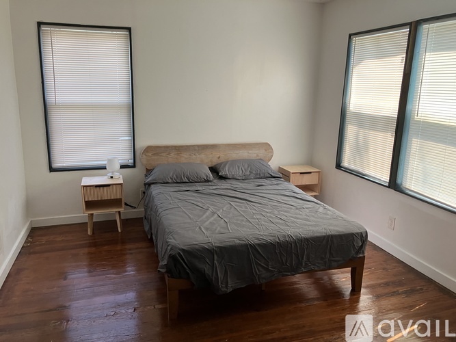 A bedroom with a bed, nightstand, and window blinds.