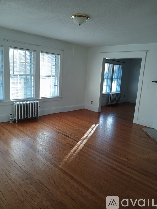 A room with wooden floors and two windows.