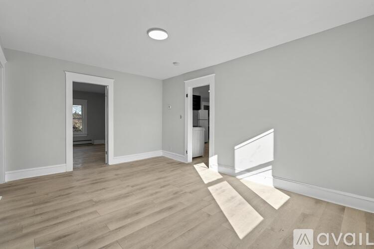 A spacious room with wooden flooring and white walls.
