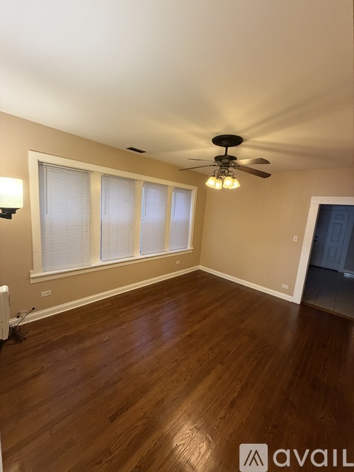 A room with a ceiling fan and wooden flooring.