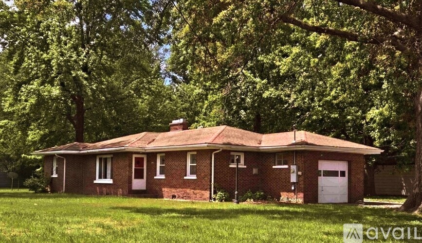 A house with a white garage door is surrounded by trees.