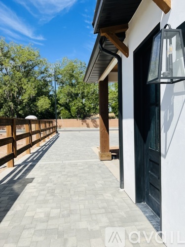 A patio with a black door and a lamp on the wall.