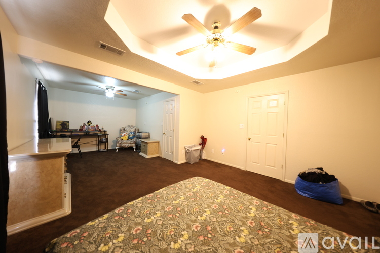 A bedroom with a ceiling fan and a bed with a floral bedspread.