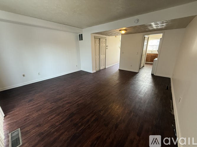 A room with wooden floors and white walls, with a door on the left and another door on the right.