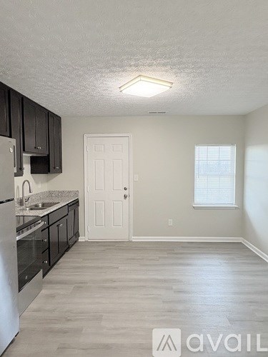 A kitchen with black cabinets and a white refrigerator.