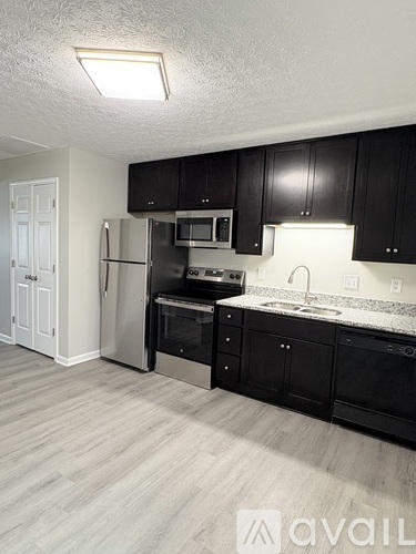 A kitchen with black cabinets and a white fridge.