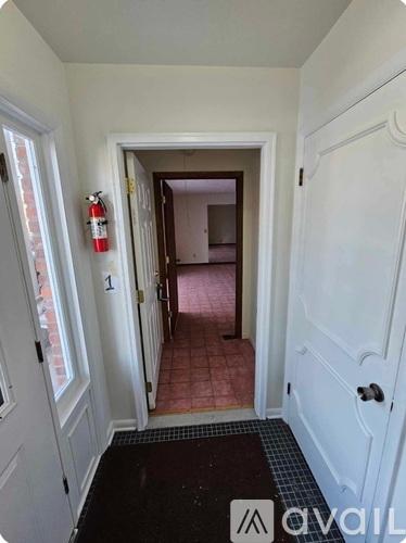 A hallway with a fire extinguisher on the wall and a number 1 on the door.