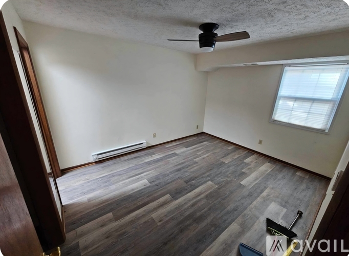 A room with a ceiling fan and wooden flooring.