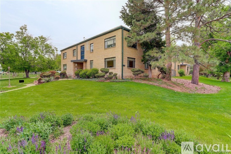 A house with a green lawn and trees in front.