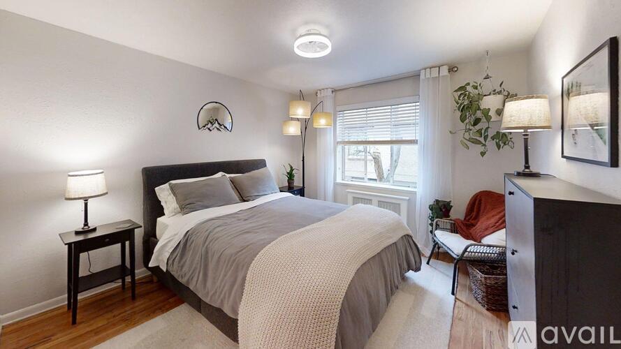 A bedroom with a large bed, a chair, and a window.