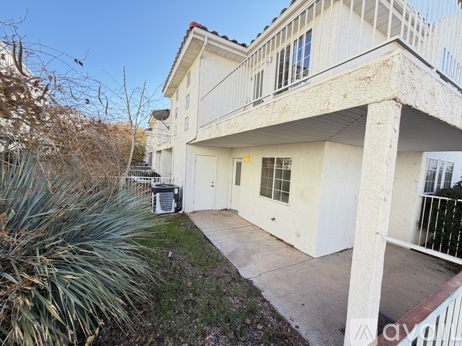 A white building with a balcony and a small garden in front.