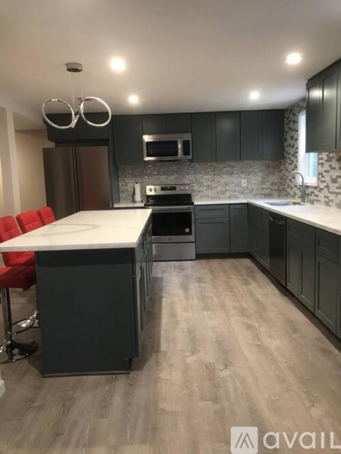 A modern kitchen with a white island and dark grey cabinets.