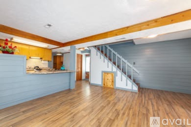 A room with wooden floors and a staircase leading to another room.