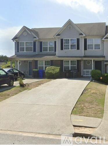 A two-story house with a grey roof and a driveway in front.