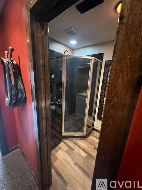 A room with a red wall and a wooden floor with a glass door.