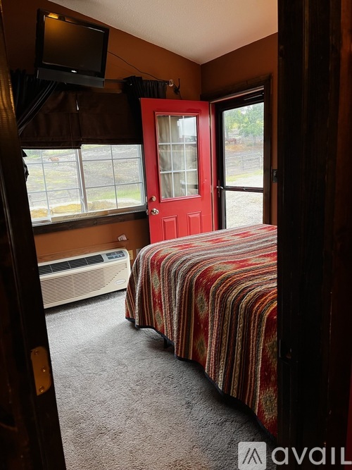 A bedroom with a red door and striped bedspread.