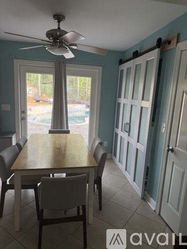 A dining room with a table and chairs and a ceiling fan.