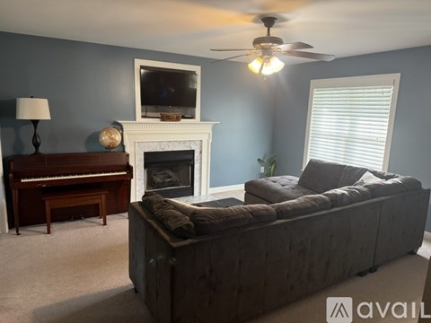 A living room with a piano, a sofa, and a fireplace.