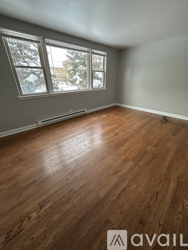 A room with wooden flooring and a window showing a snowy scene outside.