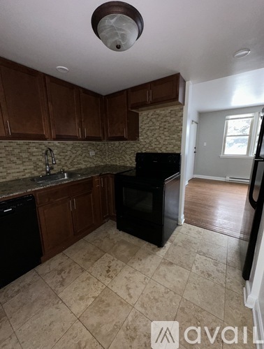 A kitchen with brown cabinets and black appliances.