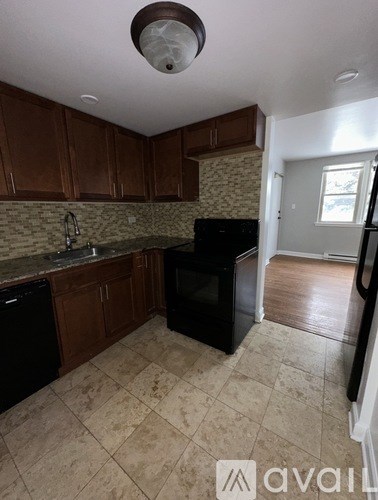 A kitchen with brown cabinets and black appliances.