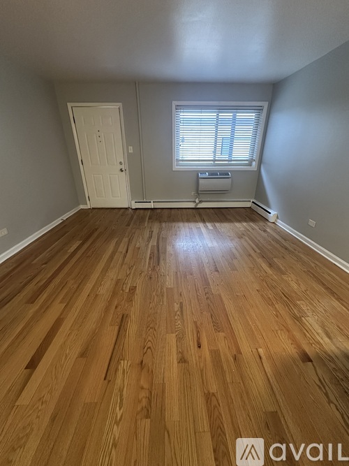 A room with wooden flooring and a window with blinds.