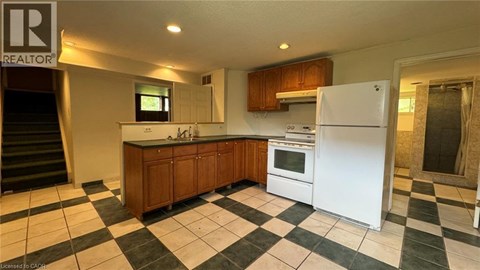 A kitchen with a white fridge and black and white checkered floor.