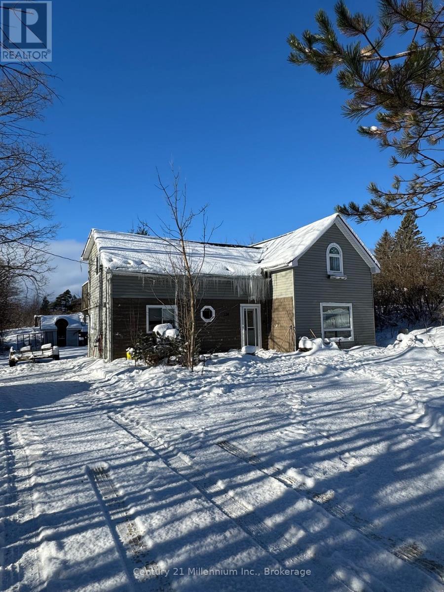 A house with a snow-covered ground and a tree in front of it.